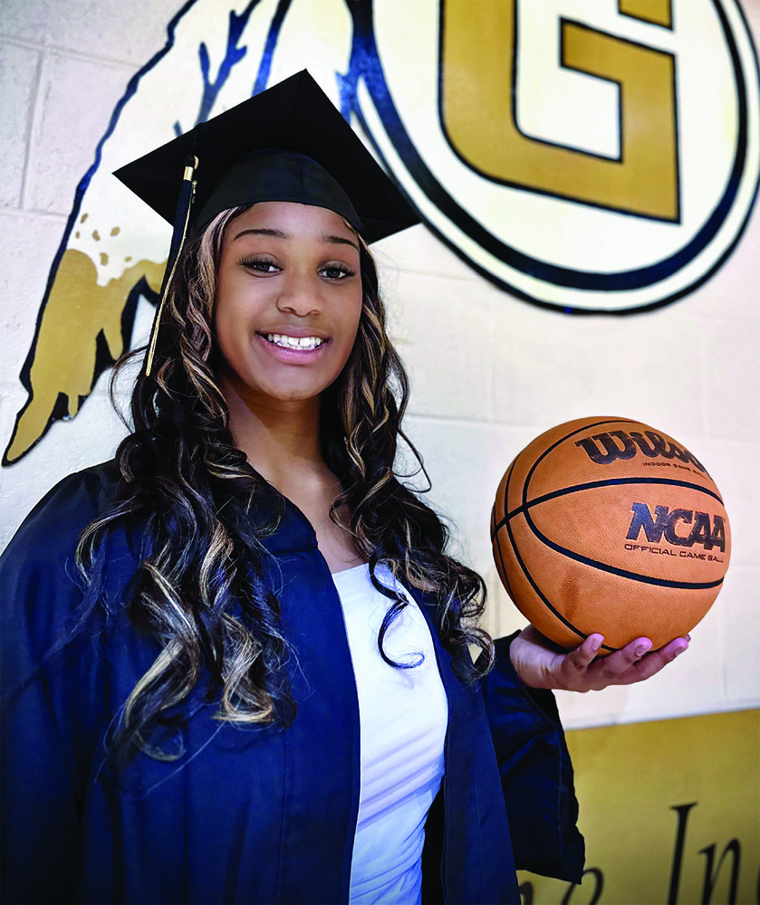 Diamynd Buckson in a cap and gown holding a basketball.